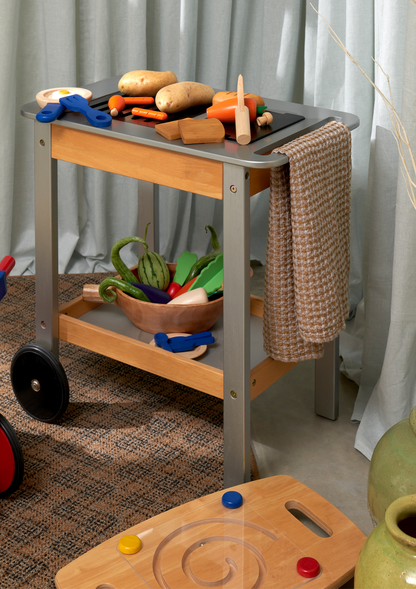 A wooden crate filled with colorful plastic vegetables, including carrots, lettuce, beetroot, and more, designed for pretend play.