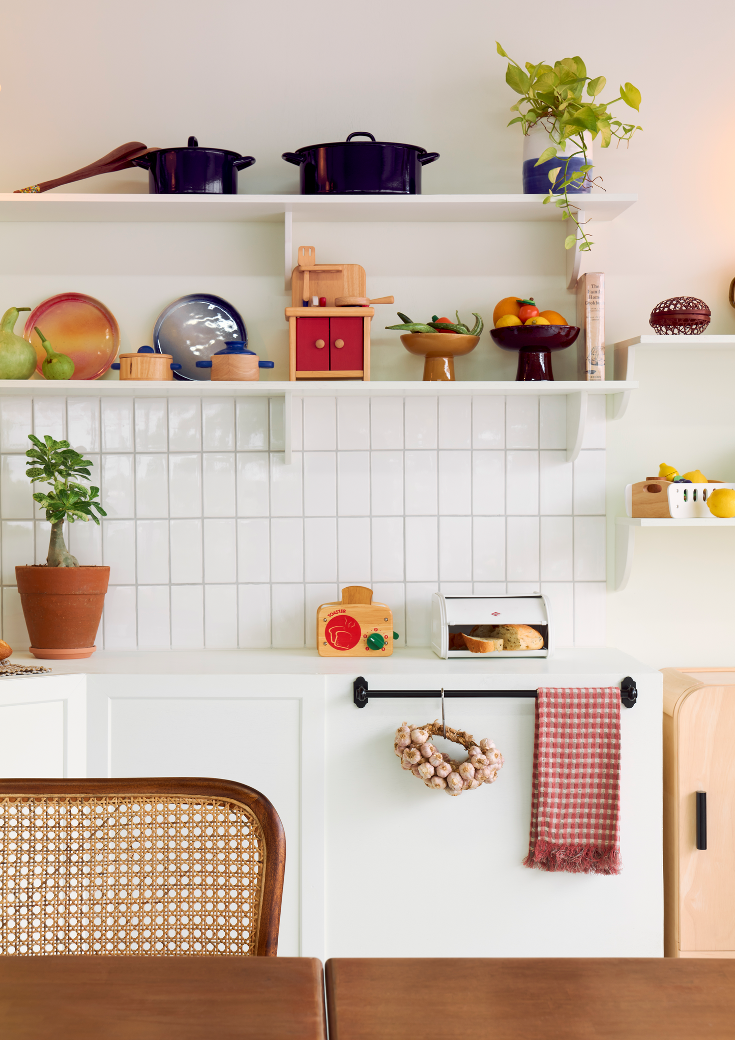 A wooden toy crate with fruits banana, grape, orange, kiwi-fruit, apple and pear, designed for children's play.