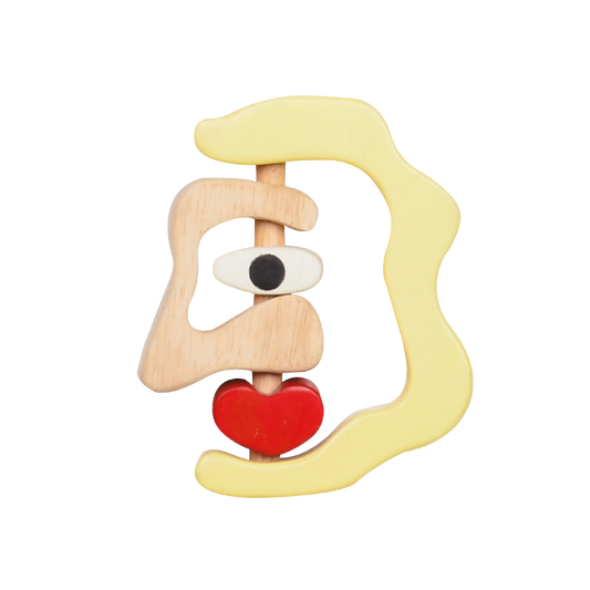 A wooden rattle in the shape of a stylized female face with a red heart detail.