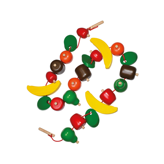 A colorful stringing toy with chunky beads shaped like fruits and a wooden needle, arranged to form a spiral.